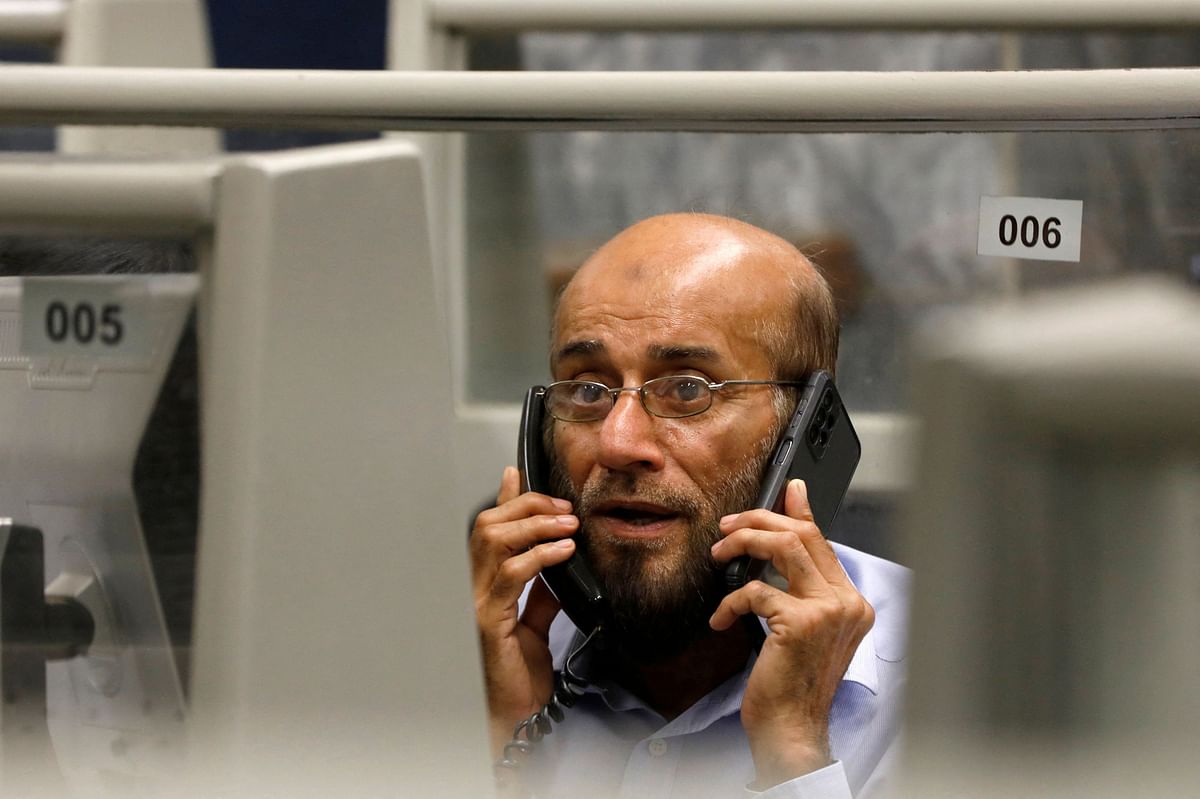 A stock broker talks on phones while monitoring the market from his booth during trading session at the Pakistan Stock Exchange, in Karachi, Pakistan July 3, 2023. REUTERS/Akhtar Soomro