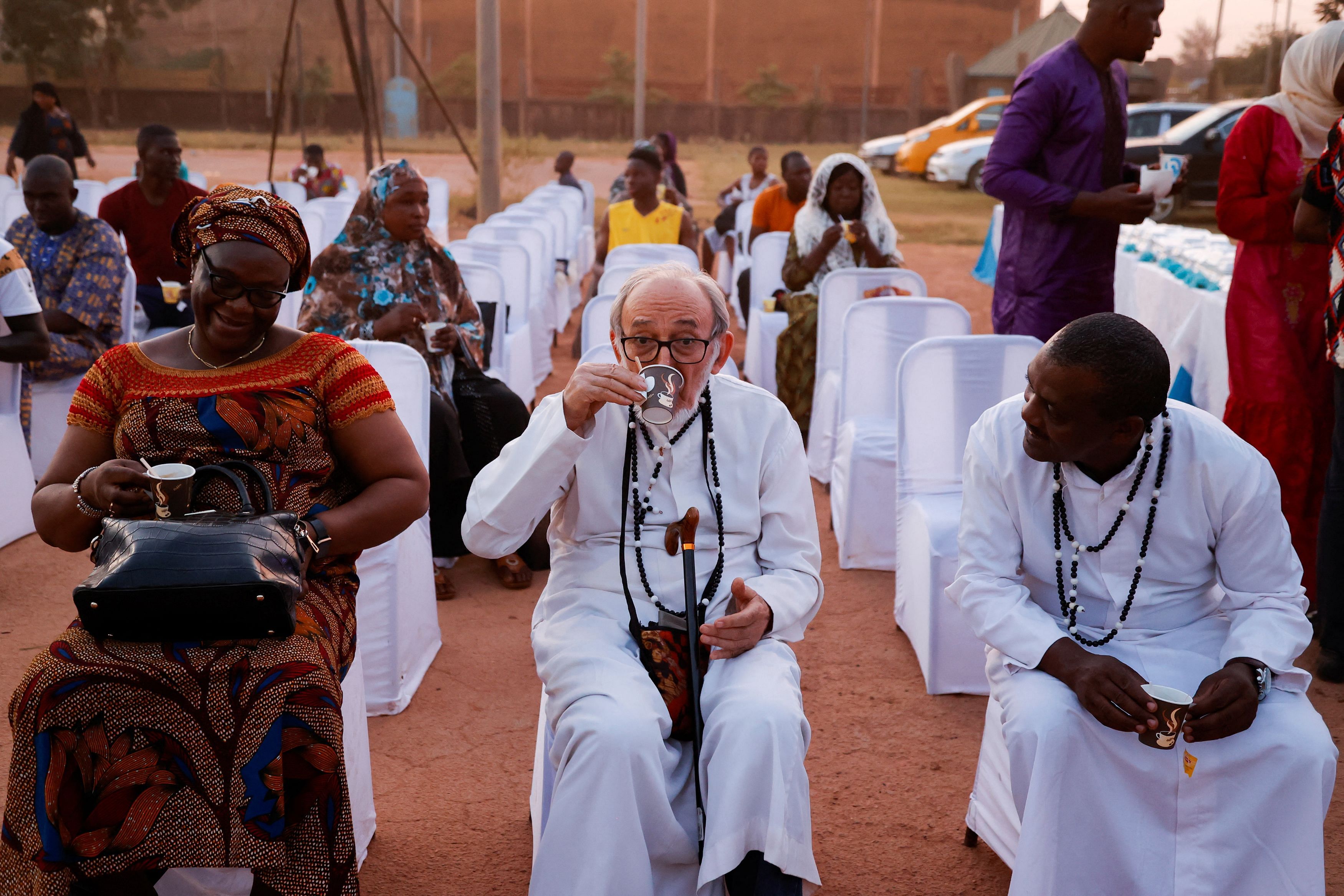 Dominic Appe, a catholic priest drinks coffee as Burkinabe Muslims and Christians gather to break the fast together in hopes of promoting religious tolerance during the Ramadan in Ouagadougou’s public square, Burkina Faso March 31, 2023.REUTERS/ Yempabou Ouoba       NO RESALES. NO ARCHIVES.