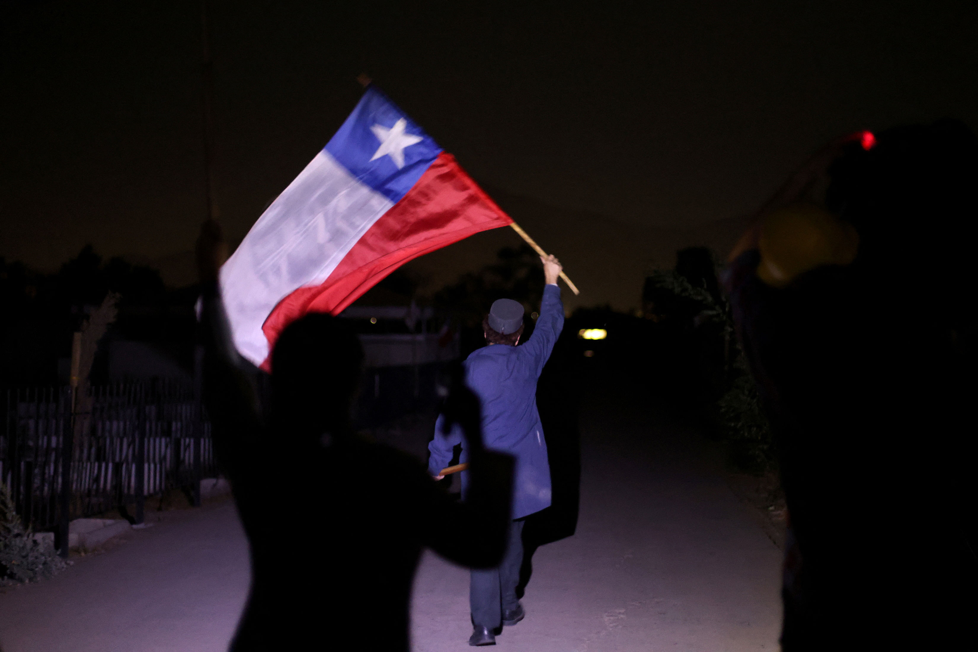 An actor portraying a gravedigger waves a Chilean flag while performing "Voces de los Patios" , a theatrical performance through the stories of witnesses and victims of the political violence during the dictatorship, ahead of the 50th anniversary of the coup d'etat in Chile that ushered in a 17-year dictatorship under the Pinochet regime, at Santiago's General Cemetery, Chile, April 2, 2023. REUTERS/Ivan Alvarado