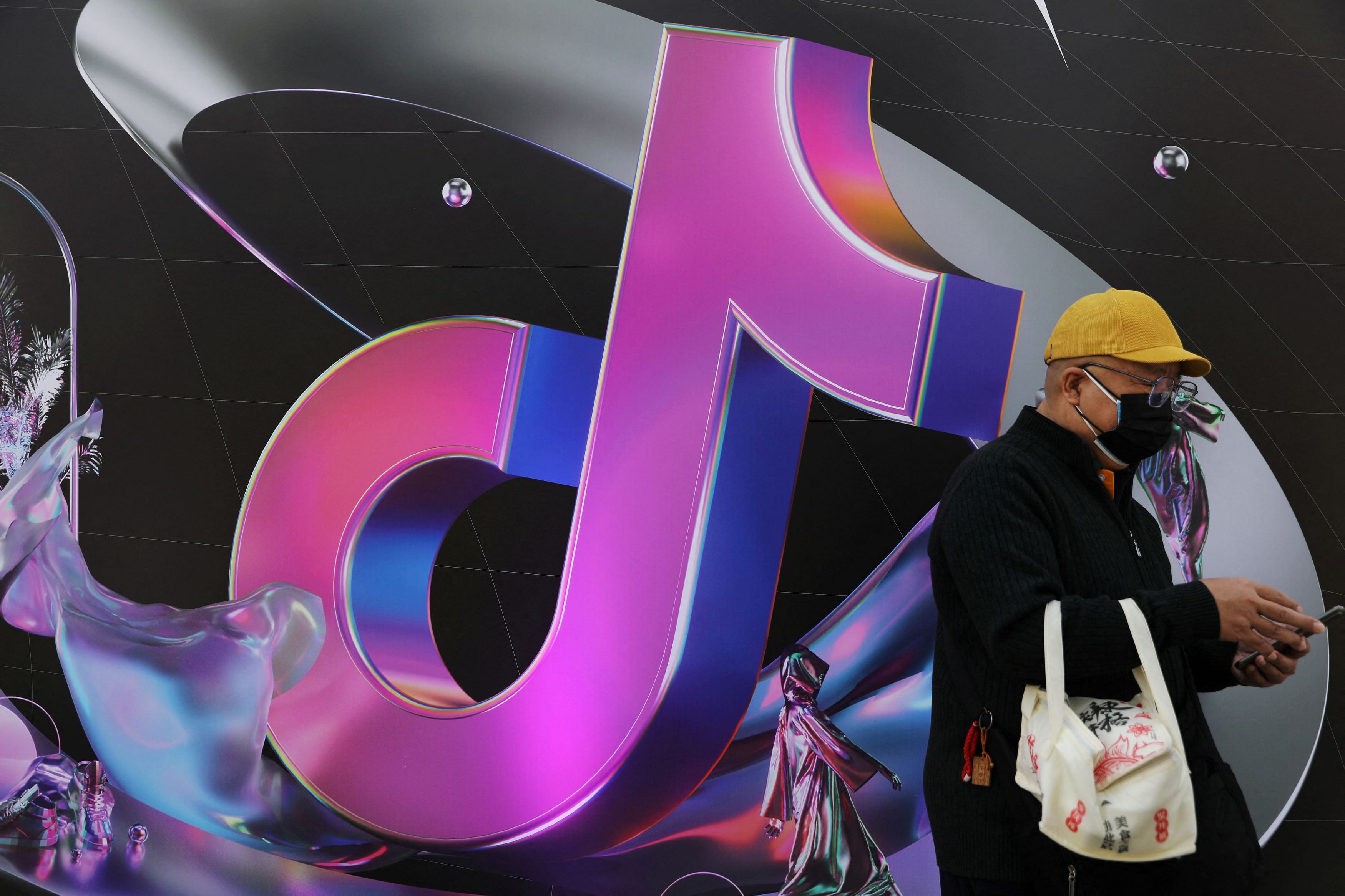 FILE PHOTO: A man stands near a sign of ByteDance app Douyin during China Fashion Week, in Beijing, China March 31, 2021. REUTERS/Tingshu Wang/File Photo