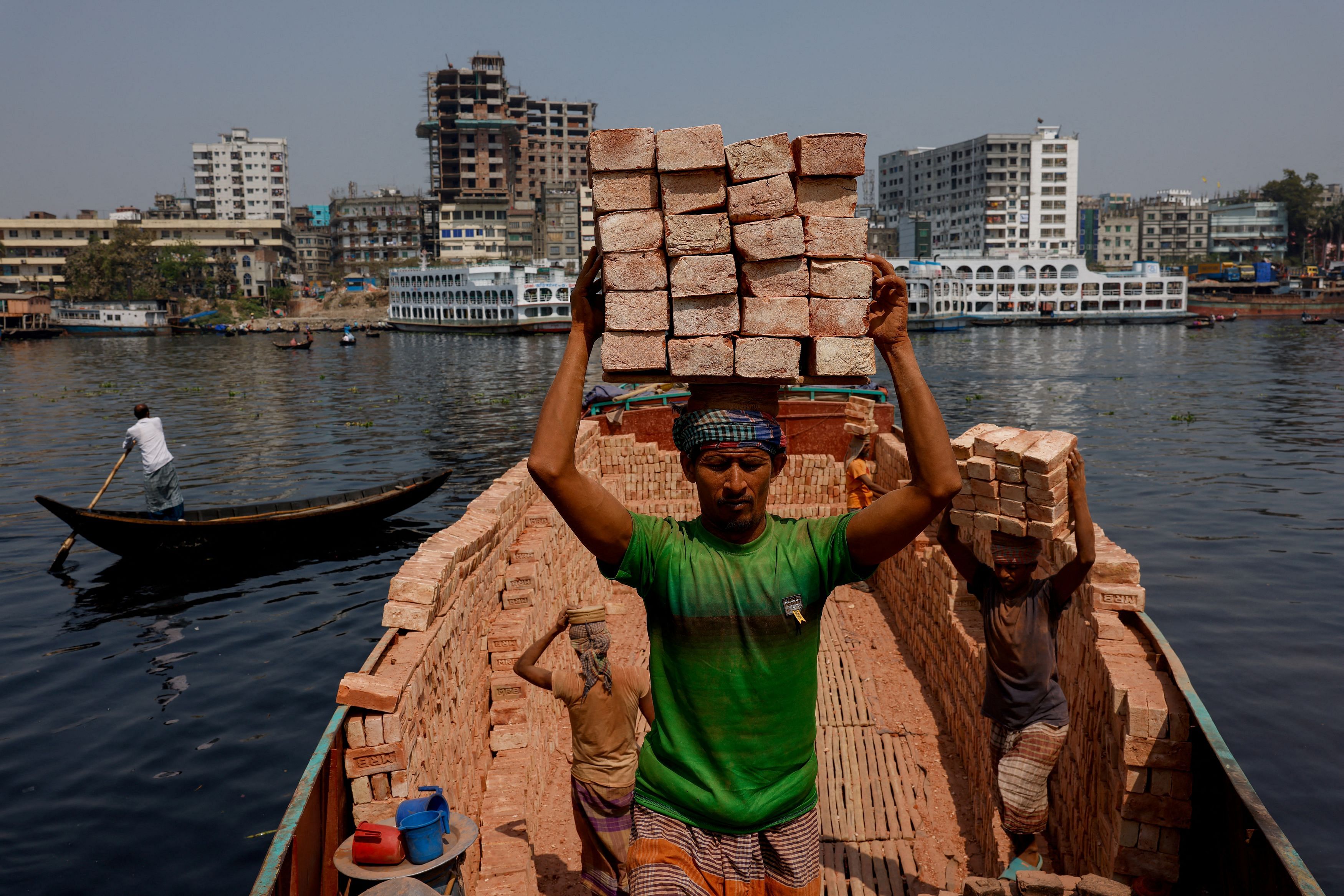 Labourers unload bricks from a trawler on the bank of the Buriganga river in Dhaka, Bangladesh, March 6, 2023. The Buriganga, or the 'Old Ganges', is so polluted that its water appears pitch black, except during the monsoon months, and emits a foul stench through the year. The South Asian nation of nearly 170 million, with about 23 million living in Dhaka, has about 220 small and large rivers and a large chunk of its population depends on rivers for a living and transport. Untreated sewage, by-products of fabric dyeing and other chemical waste from nearby mills and factories flow in daily. Polythene and plastic waste piled on the riverbed have made it shallow and caused a shift in course. REUTERS/Mohammad Ponir Hossain       SEARCH "HOSSAIN BURIGANGA POLLUTION" FOR THIS STORY. SEARCH "WIDER IMAGE" FOR ALL STORIES.     TPX IMAGES OF THE DAY