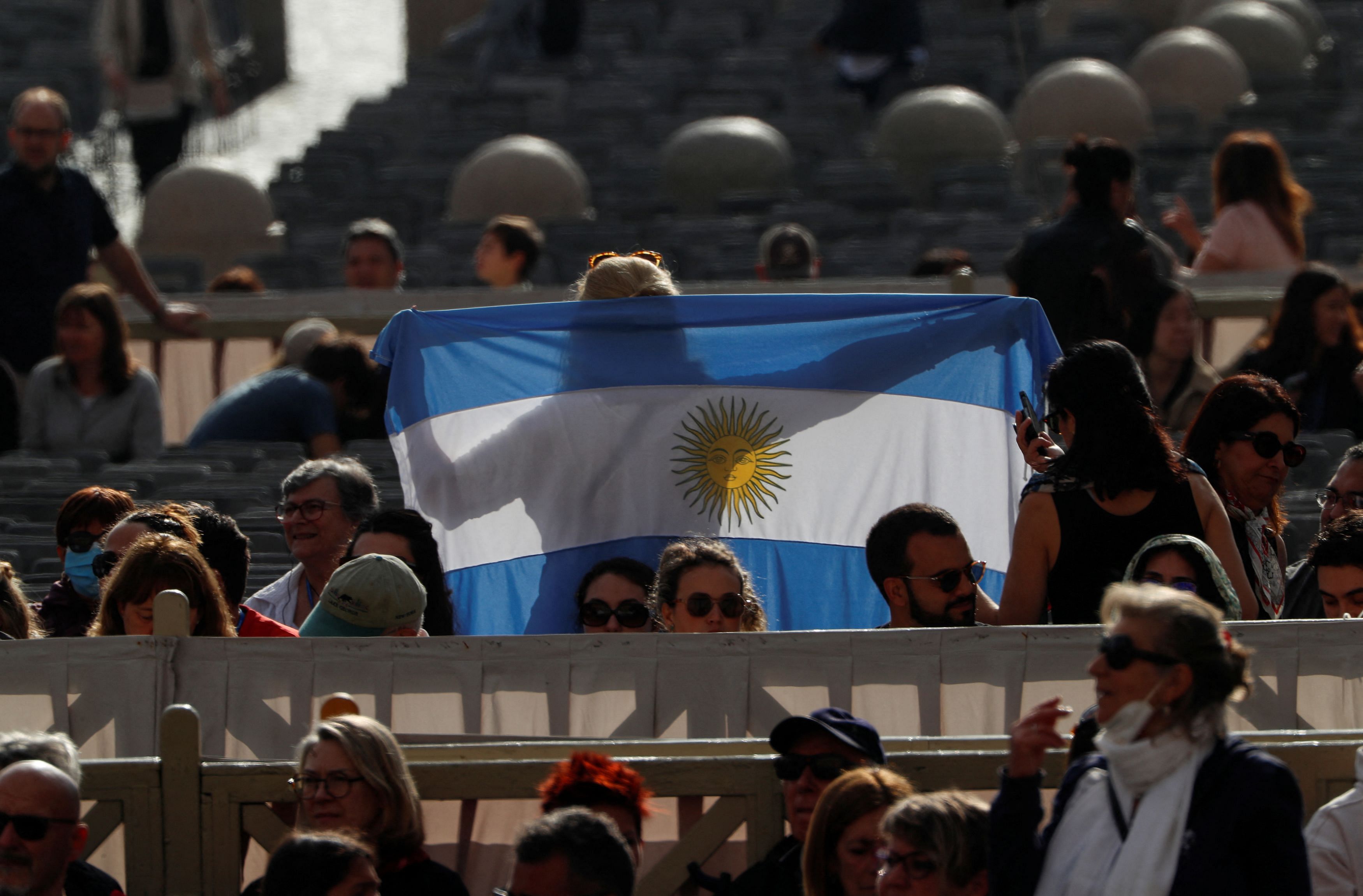 A person holds the flag of Argentina as they wait for the arrival of Pope Francis for the weekly general audience in St. Peter's Square at the Vatican, May 3, 2023. REUTERS/Remo Casilli