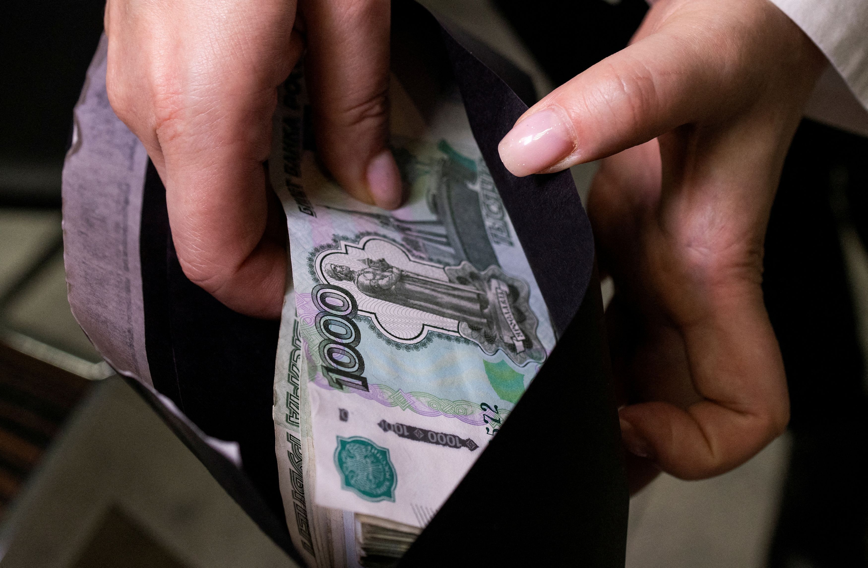 FILE PHOTO: An employee holds an envelope with Russian 1000-rouble banknotes in a bank office in Moscow, Russia, in this illustration picture taken October 9, 2023. REUTERS/Maxim Shemetov/Illustration/File Photo