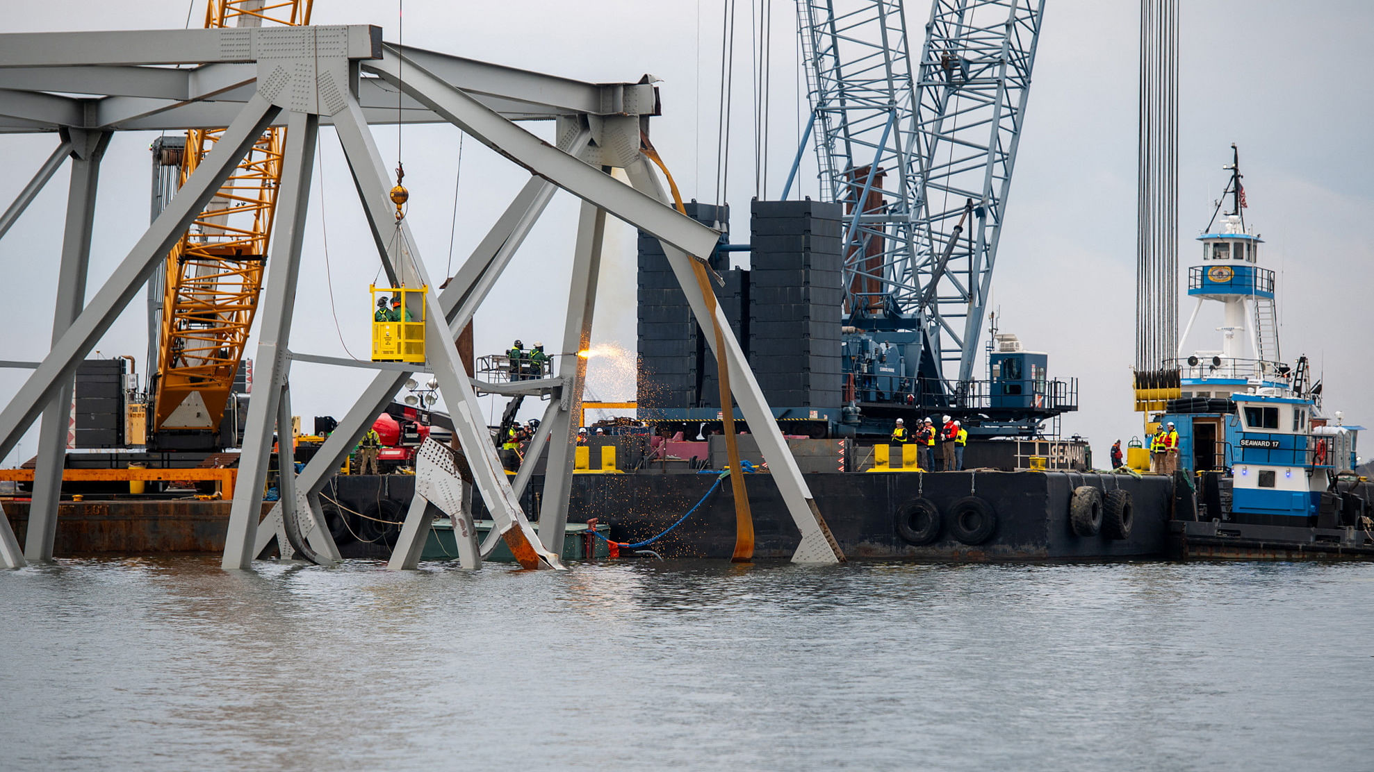 Demolition crews cut the top portion of the north side of the collapsed Francis Scott Key bridge into smaller sections for safe removal by crane in the Patapsco River, in Baltimore, Maryland, U.S. March 30, 2024.  U.S. Coast Guard/Petty Officer 3rd Class Kimberly Reaves/Handout via REUTERS THIS IMAGE HAS BEEN SUPPLIED BY A THIRD PARTY