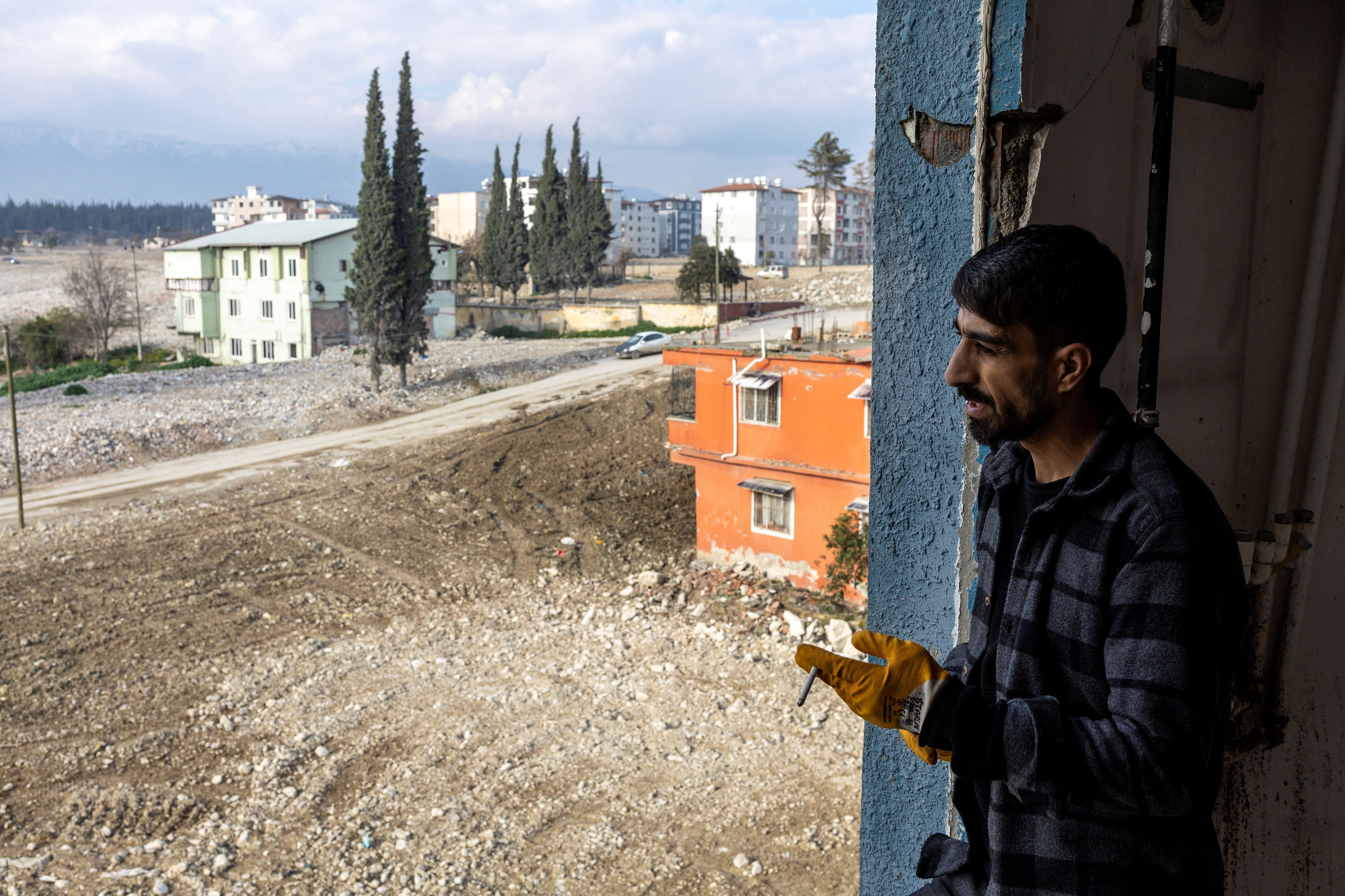 Ahmet Altinoz stands beside a window of his house, after his family received a text message telling  that the government is transferring their property to the Treasury under a new urban transformation law, in Hatay, Turkey, February 2, 2024. REUTERS/Umit Bektas