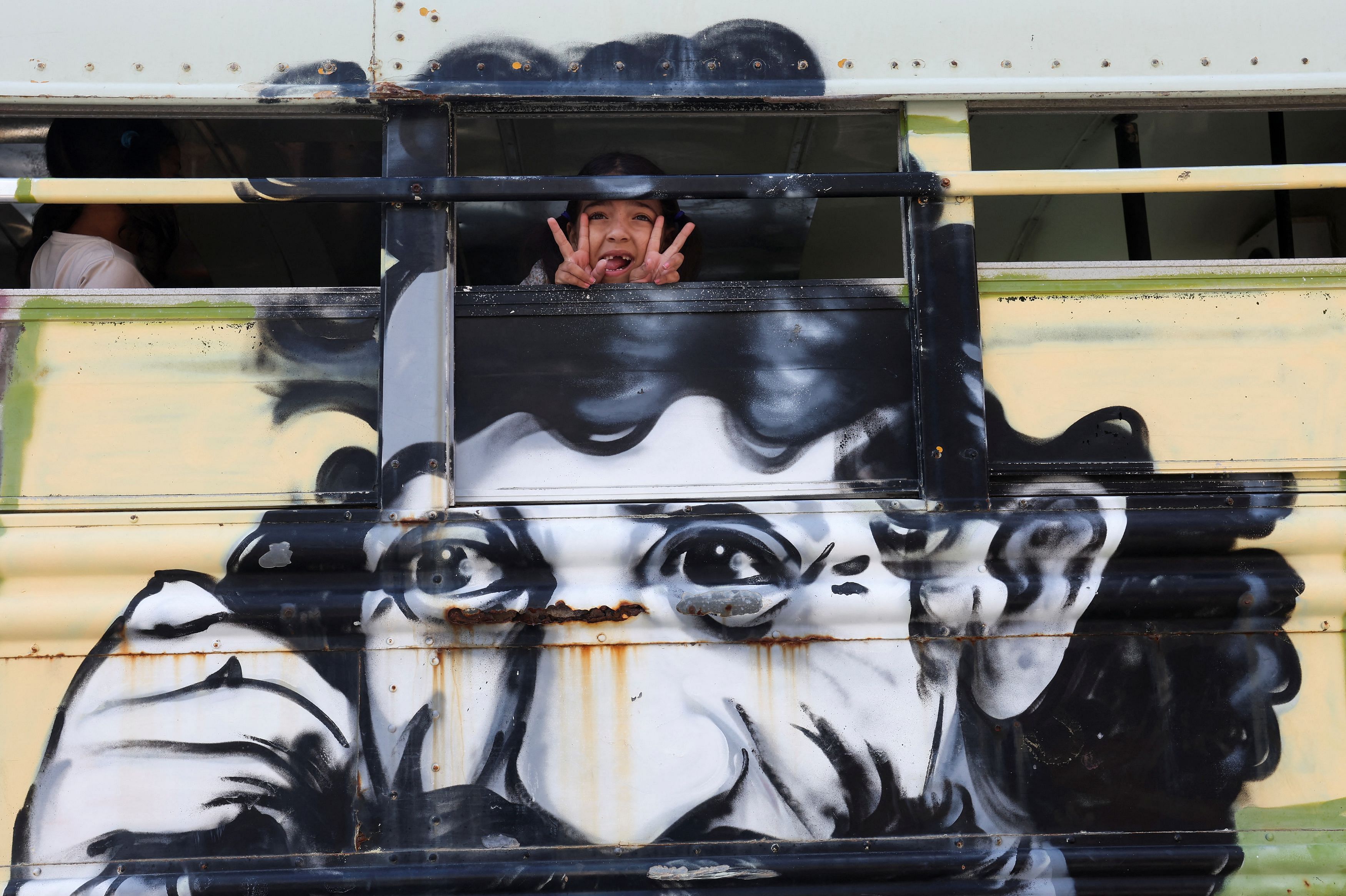 A girl gestures from the 'Peace Art Bus' transporting displaced children, who fled with their families from their border villages due to cross-border hostilities between Hezbollah and Israeli forces, to a theatre, where they will participate in entertaining activities for Eid al-Fitr, which marks the end of the Muslim holy fasting month of Ramadan, in Tyre, southern Lebanon April 9, 2024. REUTERS/Aziz Taher