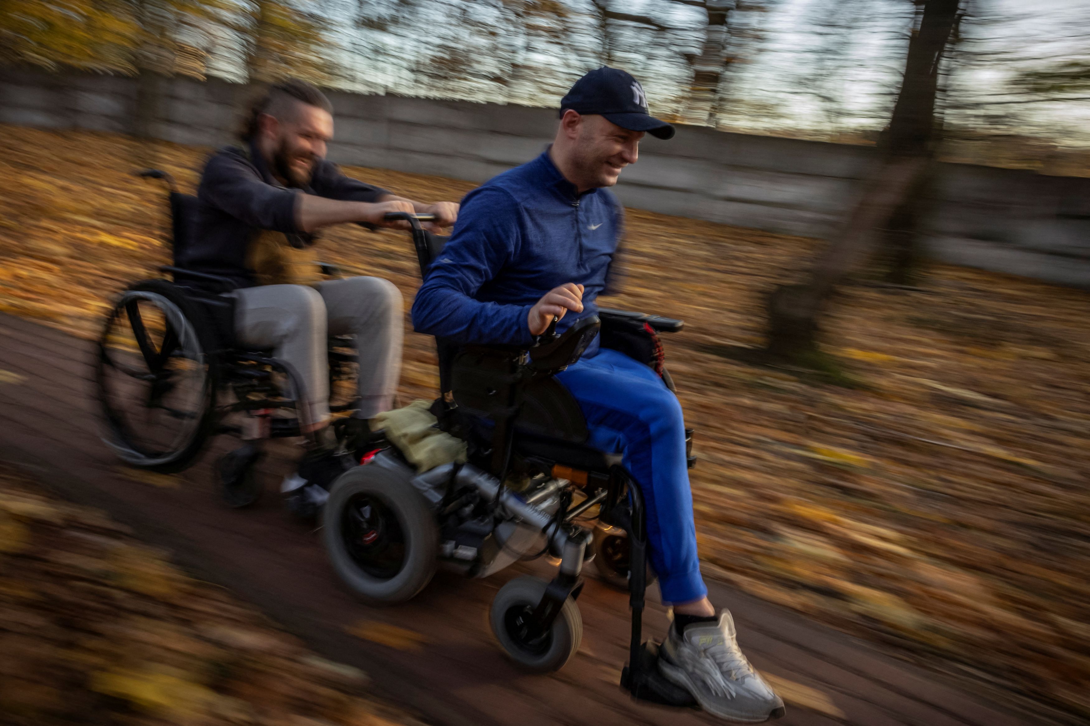 Oleksandr Revtiukh , 33, a Ukrainian serviceman who lost his left arm and most of his left leg in multiple mine blasts in 2023, pulls fellow wheelchair-bound veteran Bohdan Tanchyn with his electric wheelchair, in the garden of the Recovery Rehabilitation Center, amid Russia's attack on Ukraine, in Kyiv, Ukraine October 31, 2023. Eight months after losing his left arm and most of his left leg in mine blasts while fighting in Ukraine, Revtiukh's old life is gone. Only two years ago he had enjoyed a comfortable civilian life as an electronics technician abroad, before he returned to Ukraine to sign up and fight the Russian invasion. Now he has to accept what has happened to him and learn to live without his lost limbs. "It's like being a newborn child," he said. "You've got to get to know the world from scratch." REUTERS/Thomas Peter        SEARCH "THOMAS UKRAINE AMPUTEES" FOR THIS STORY. SEARCH "WIDER IMAGE" FOR ALL STORIES.