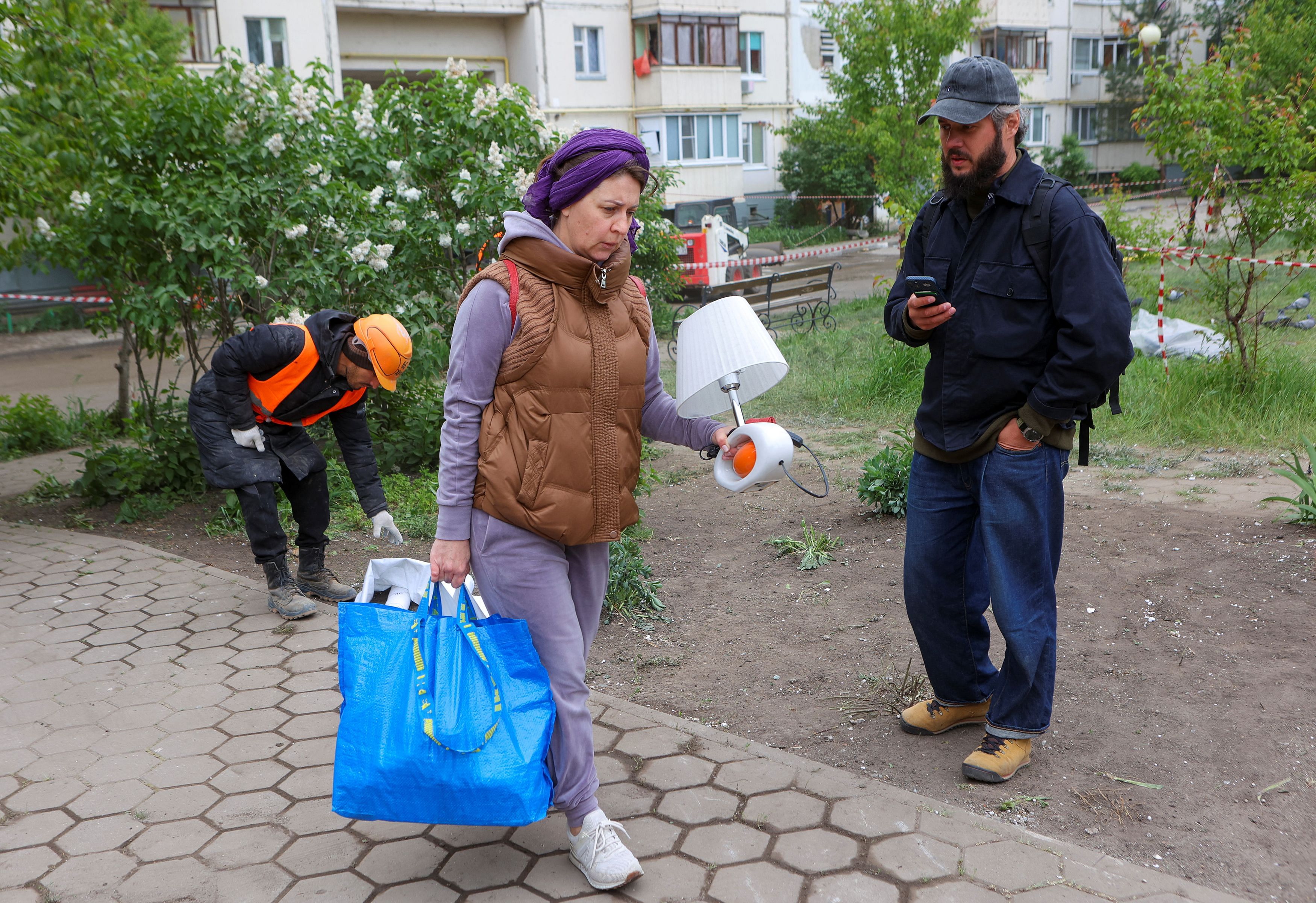 A local resident carries belongings while leaving a damaged multi-story apartment block, a section of which collapsed as the result of what local authorities called a Ukrainian missile strike, in the course of Russia-Ukraine conflict in the city of Belgorod, Russia, May 13, 2024. REUTERS/Stringer