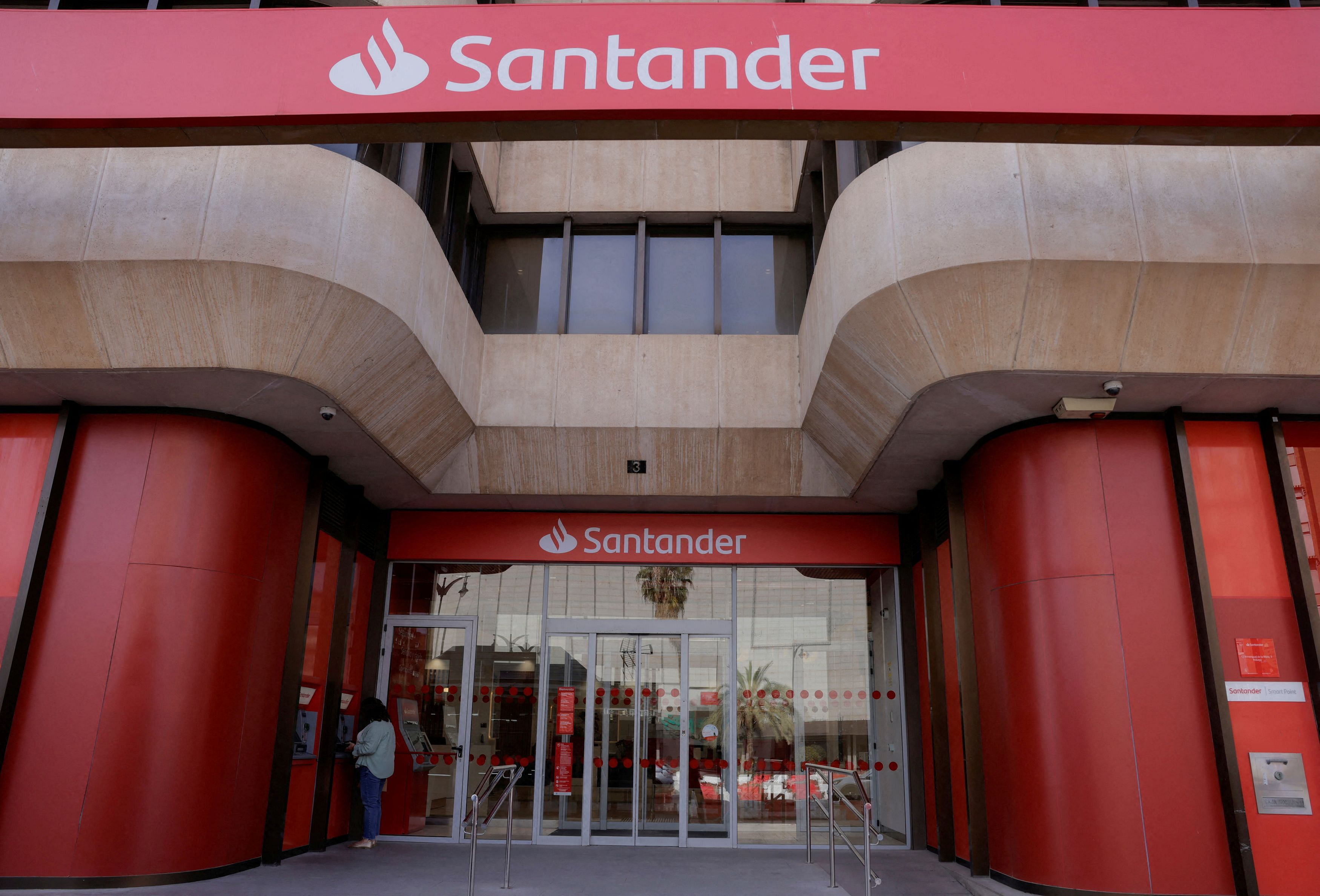 FILE PHOTO: A woman uses an ATM machine at a Santander bank branch office in Malaga, Spain, April 24, 2024. REUTERS/Jon Nazca/File Photo