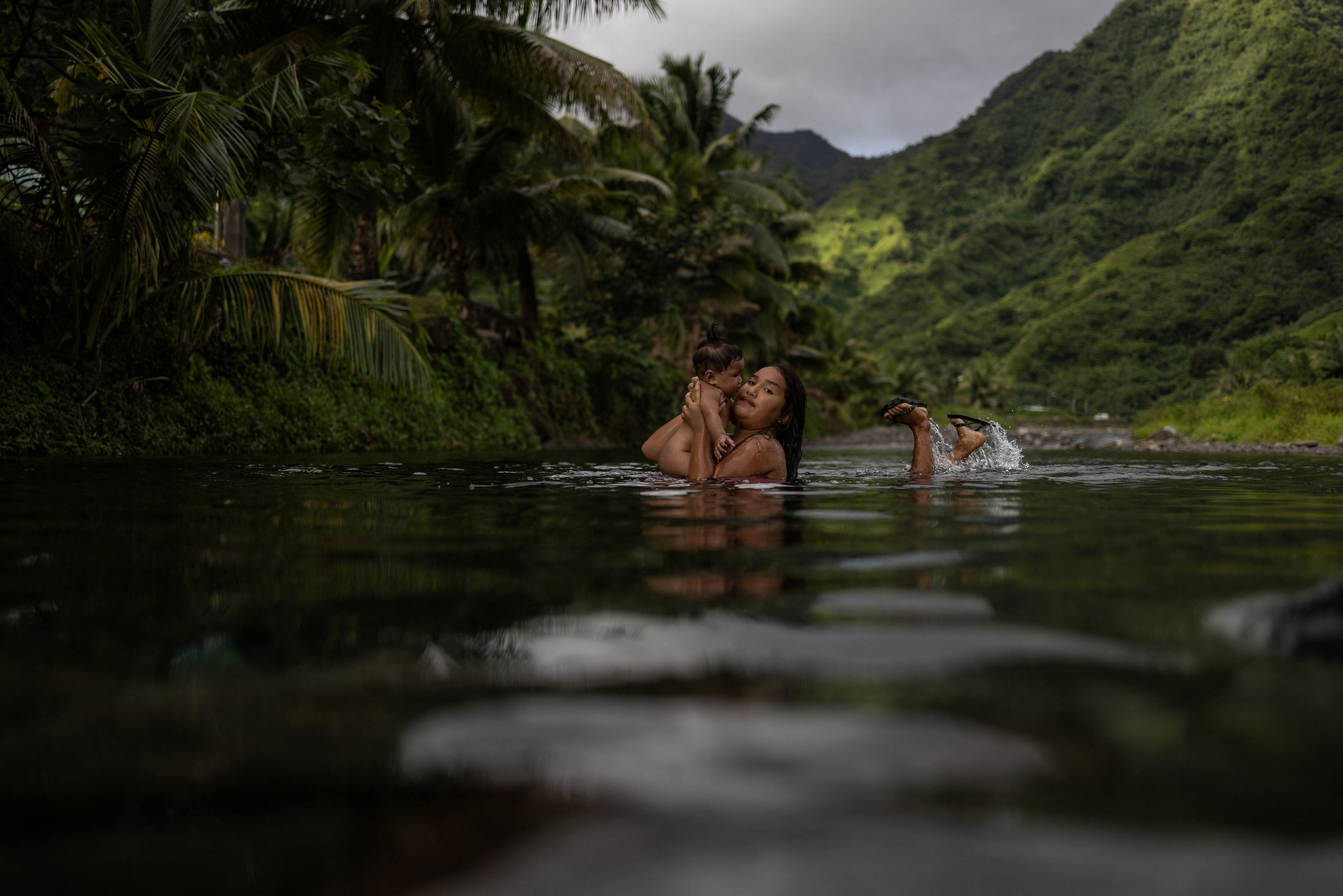 <div class="paragraphs"><p>Uratua holds six-month-old Kiana as they play inside a freshwater stream in Teahupo'o, Tahiti, </p></div>