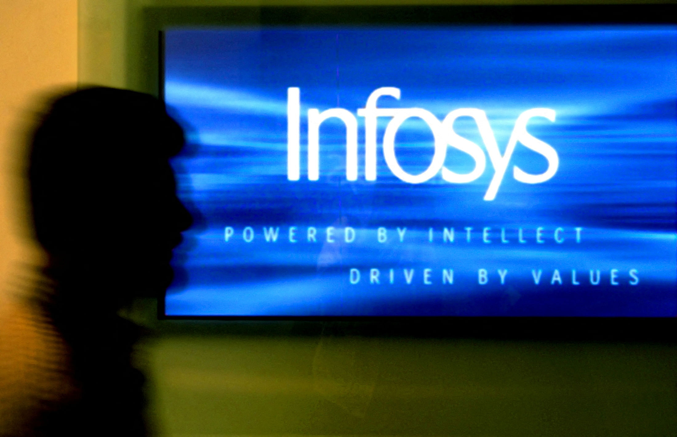 FILE PHOTO: A man walks past a billboard of Infosys Technologies Ltd's office in Bangalore, capital of the southern state of Karnataka, October 10, 2003. REUTERS/Jagadeesh NV/FA//File Photo