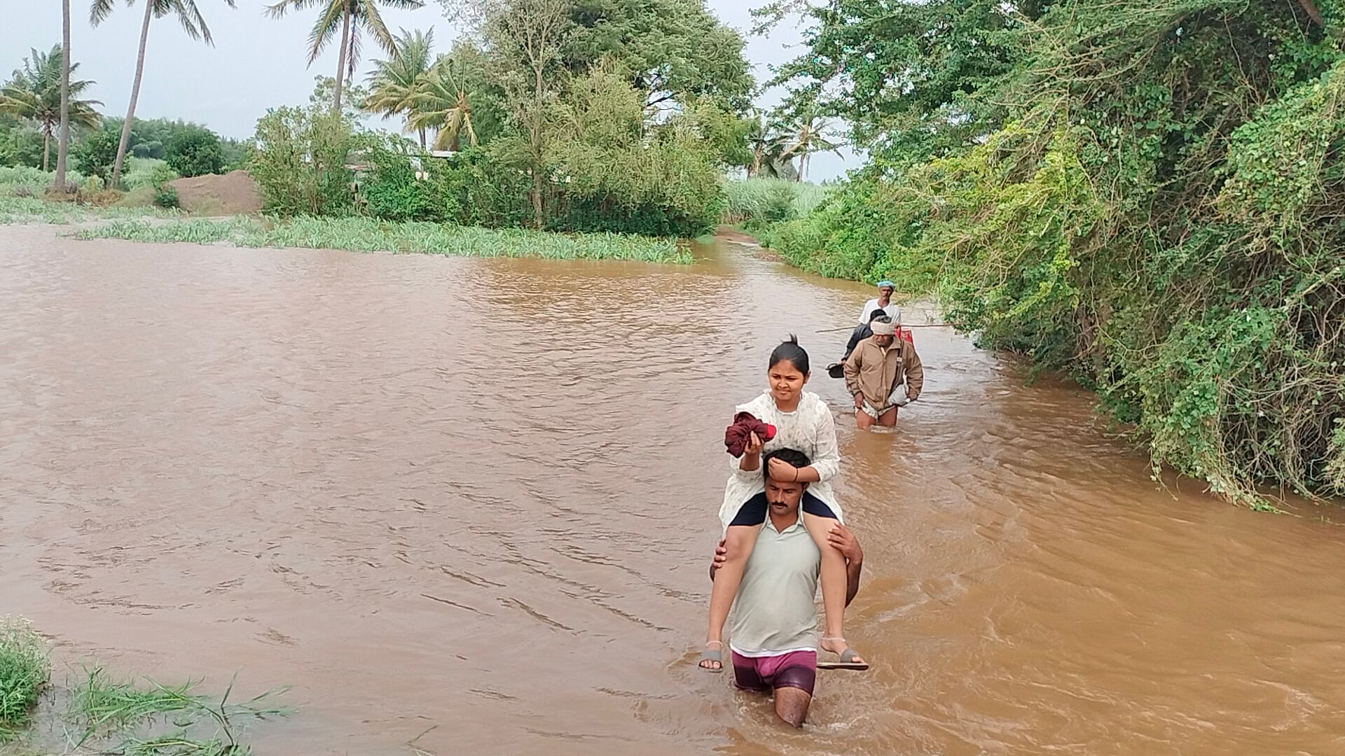 ಜಮಖಂಡಿ ತಾಲ್ಲೂಕಿನ ಮುತ್ತೂರು ನಡುಗಡ್ಡೆಯ ಜನರು ಜಲಾವೃತಗೊಂಡ ರಸ್ತೆ ದಾಟಿದರು