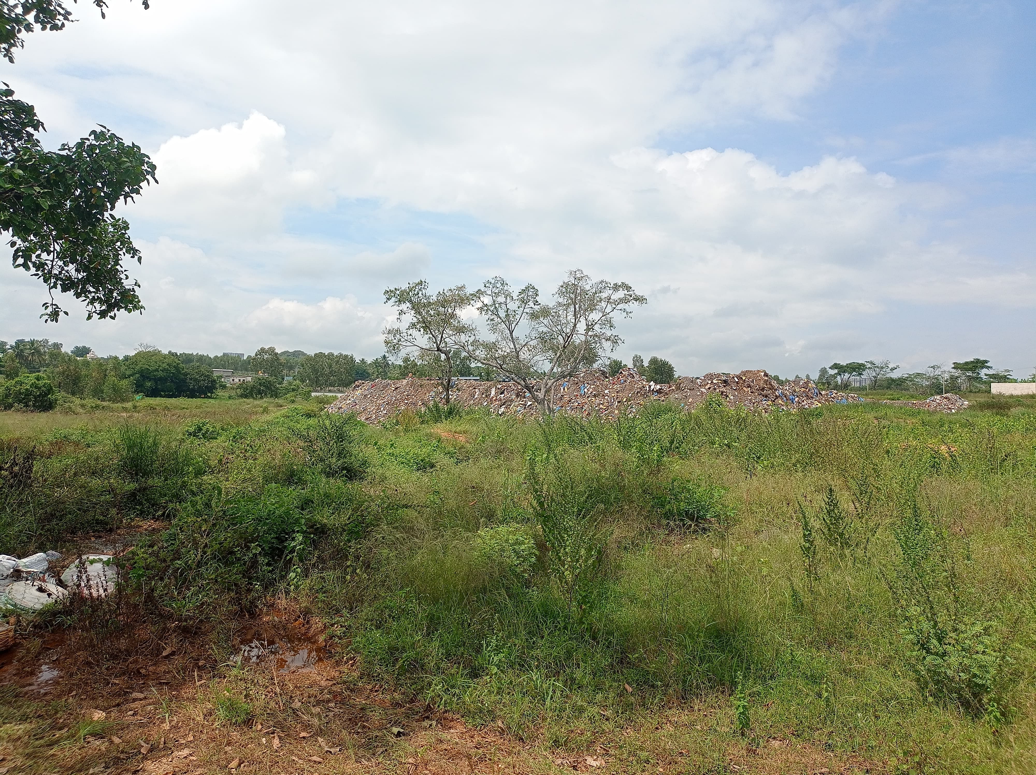 ಜಮೀನಿನಲ್ಲಿ ಸುರಿದಿರುವ ತ್ಯಾಜ್ಯದ ರಾಶಿ