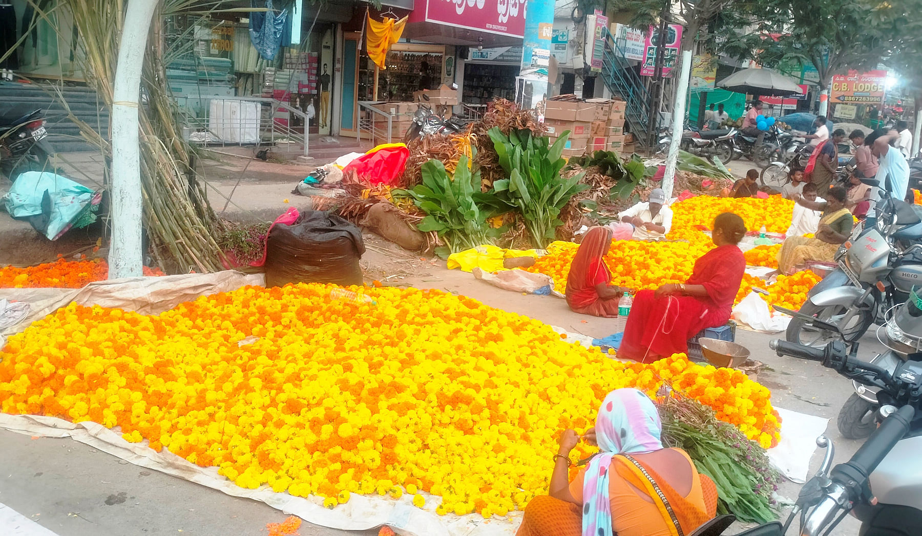 ಸಿಂಧನೂರಿನ ಮಿನಿವಿಧಾನಸೌಧ ಮುಂಭಾಗದ ಮುಖ್ಯರಸ್ತೆಯಲ್ಲಿ ವಿವಿಧ ಬಗೆಯ ಹೂವುಗಳ ಮಾರಾಟದಲ್ಲಿ ತೊಡಗಿರುವ ಮಹಿಳೆಯರು