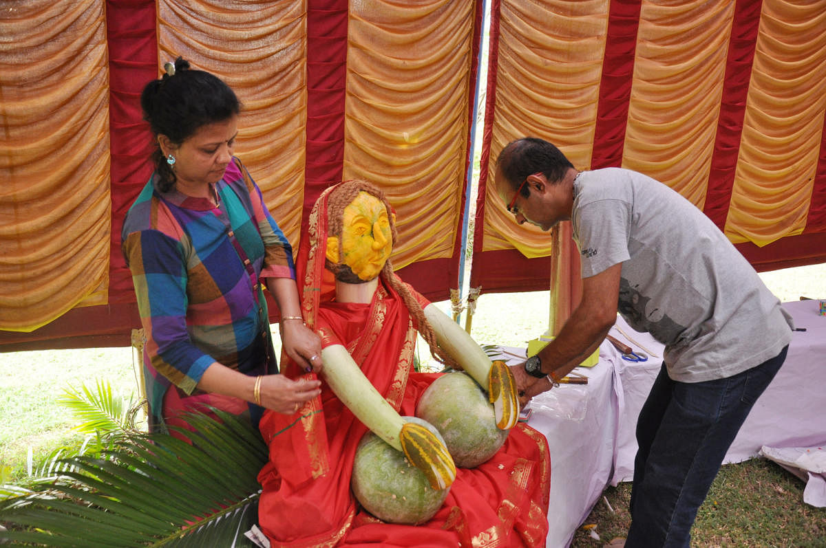 ಕುಂಬಳಕಾಯಿಯ ವೀಣೆ ನುಡಿಸುವ ಶಾರದೆ ತಯಾರಿಕೆಯಲ್ಲಿ ನಿರತರಾಗಿರುವ ಹರೀಶ್ ಕುಮಾರ್‌ ದಂಪತಿ.