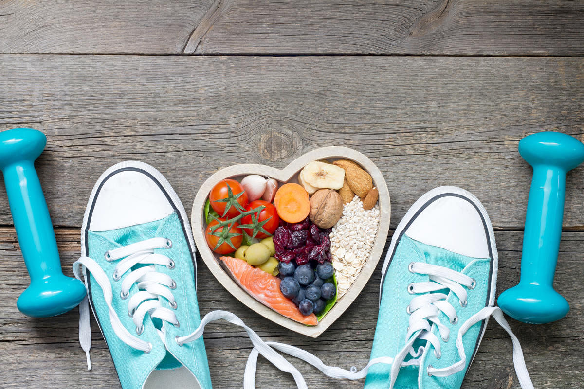 Healthy lifestyle concept with food in heart and sports fitness accessories on wooden boardsHeart