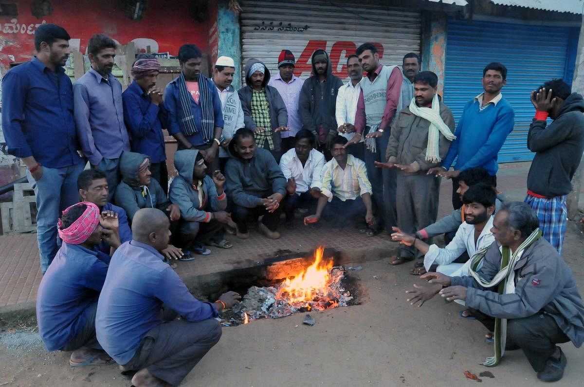 ಚಳಿಯಿಂದ ಪಾರಾಗಲು ರಸ್ತೆ ಬದಿಯಲ್ಲಿ ಬೆಂಕಿ ಮುಂದೆ ಮೈ ಕಾಯಿಸುತ್ತಿರುವುದು.