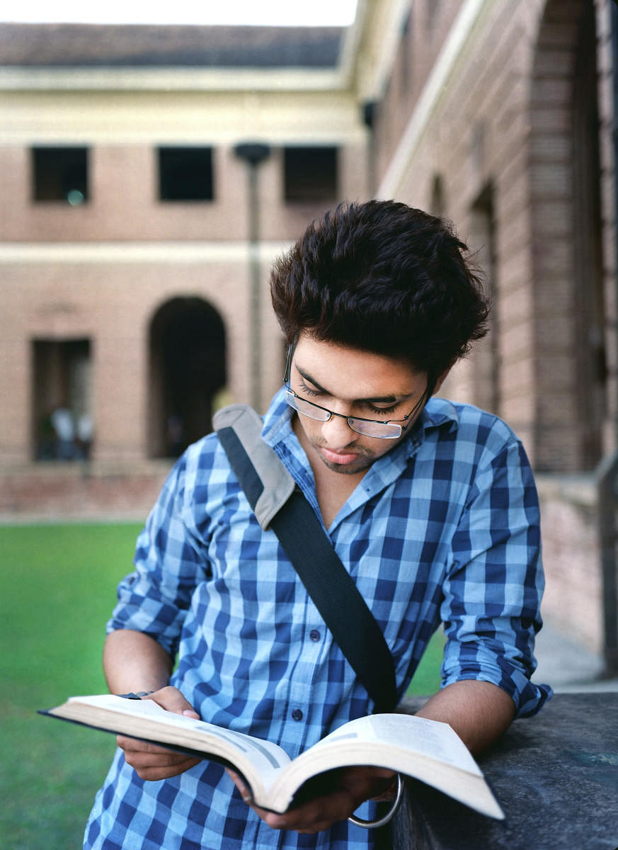 Young Male College student reading his notes before examination outside the campus.lead 