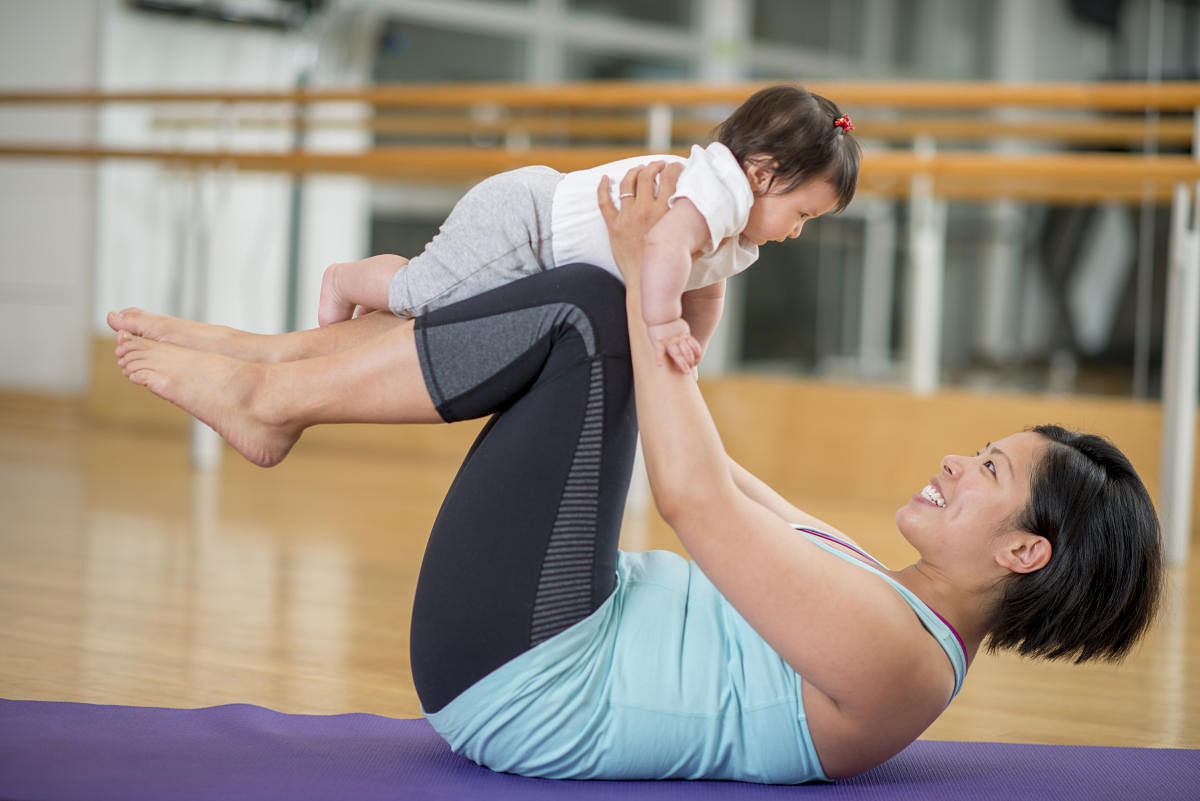A mother working out, doing yoga and stretching, at a gym while holding her baby daughter.baby and Mother Yoga