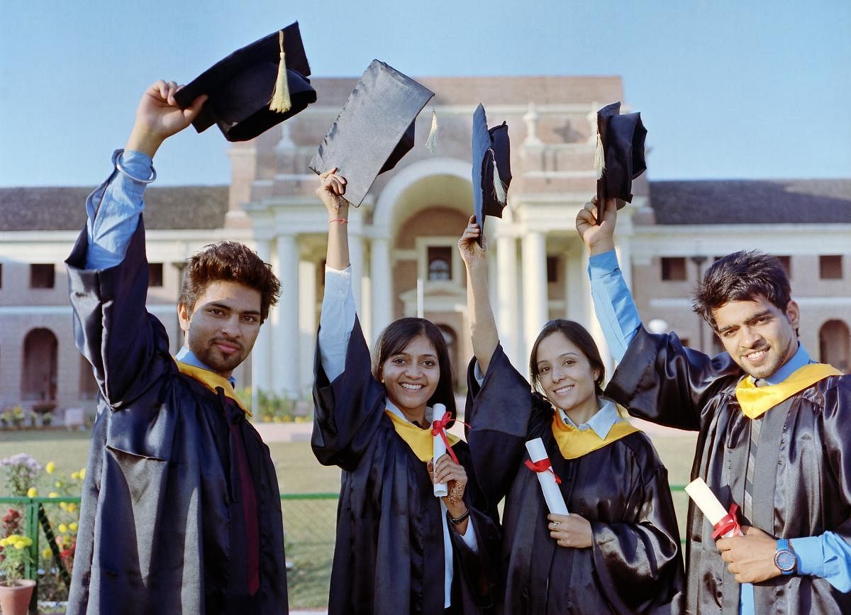 Team of successful university graduates raising their convocation caps.