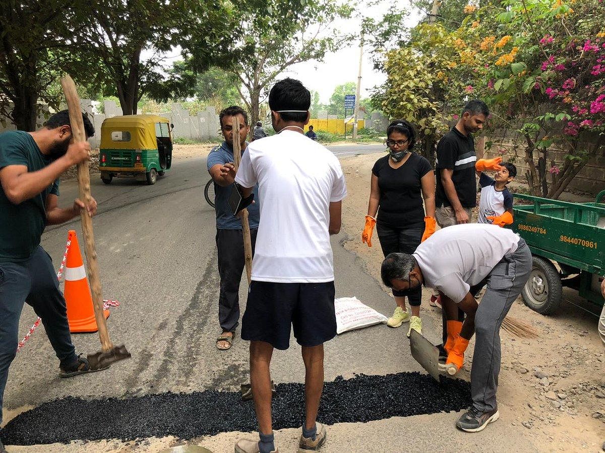 ಹರಳೂರು ರಸ್ತೆಯಲ್ಲಿದ್ದ ಗುಂಡಿಯನ್ನು ಮುಚ್ಚುತ್ತಿರುವ ಸ್ಥಳೀಯ ನಿವಾಸಿಗಳು