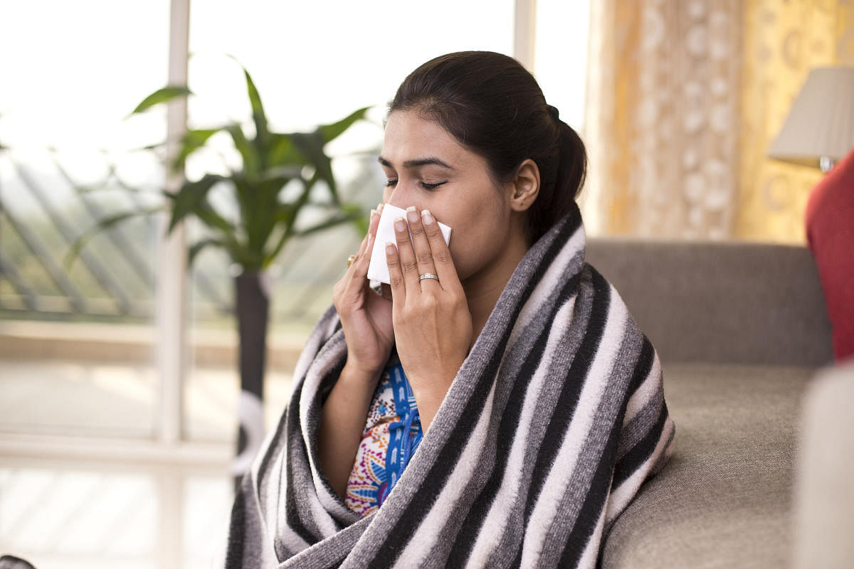 Sick woman sitting at home and blowing her noseSickness Cold