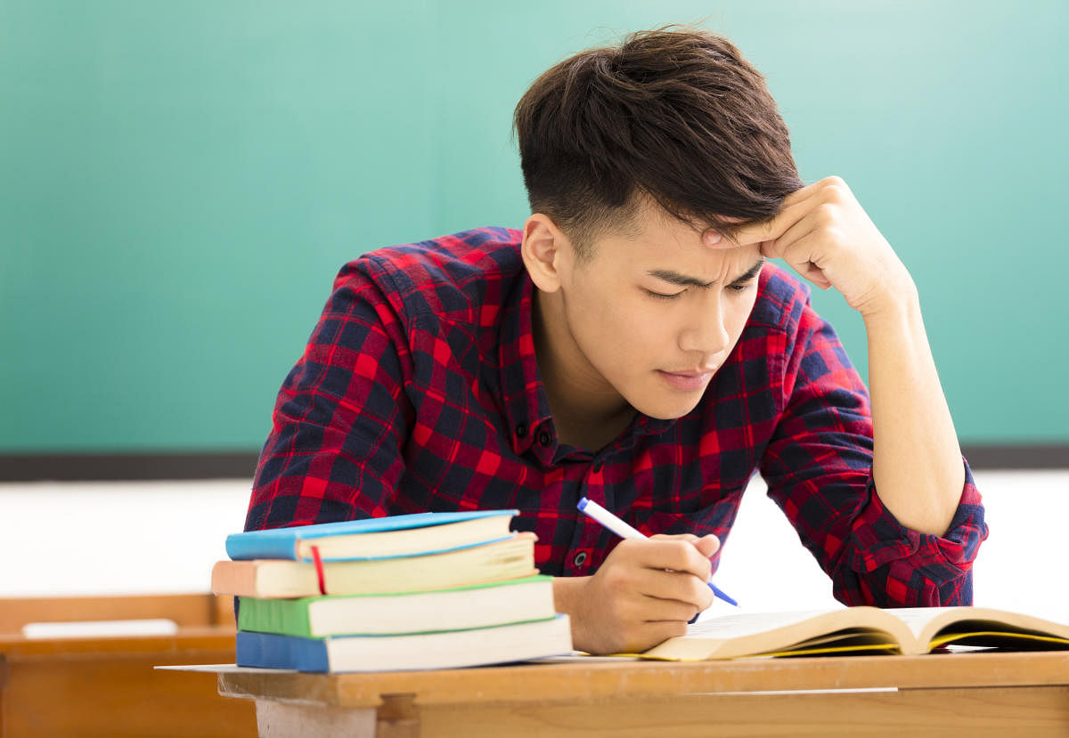 Stressed student studying for exam in classroom