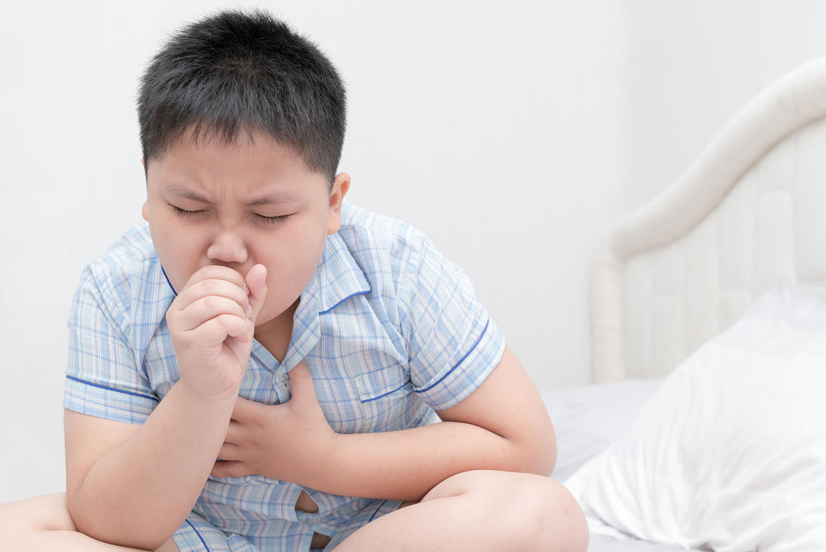 Sick obese boy is coughing and throat infection on bed, health care conceptSick obese boy is coughing and throat infection on bed, health care concept