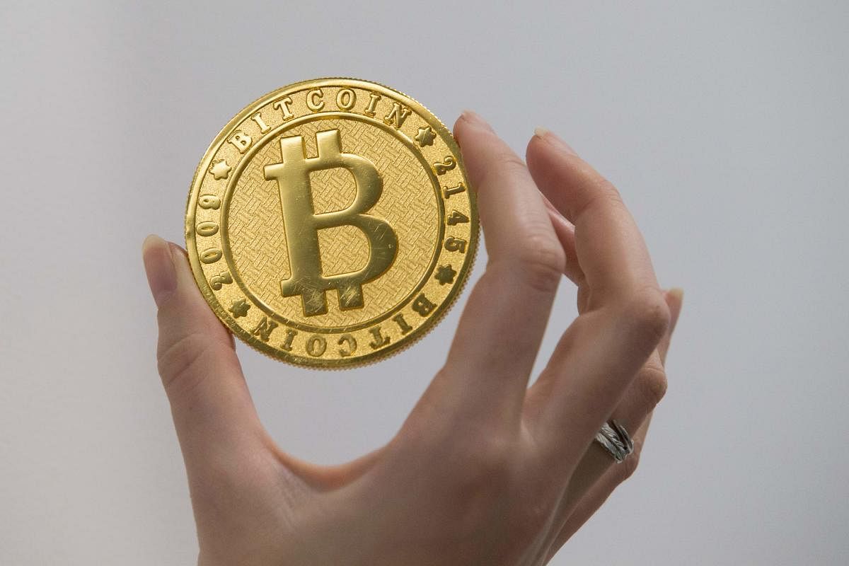 A person holds on January 17, 2018 shows a visual representation of the digital cryptocurrency Bitcoin, at La Maison du Bitcoin in Paris. / AFP PHOTO / GEOFFROY VAN DER HASSELT
