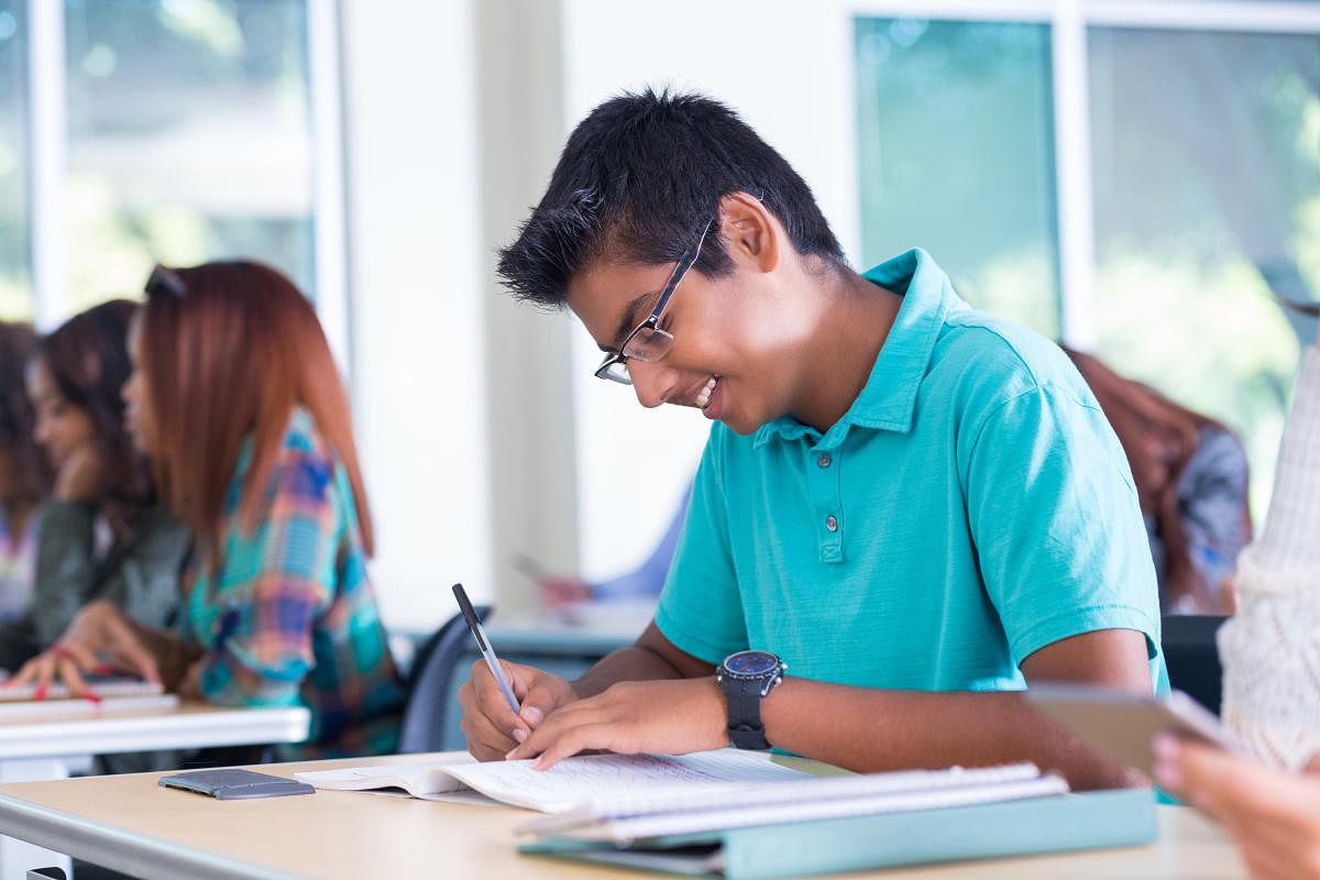 Smart Indian student taking notes during high school classEducation Related Photos