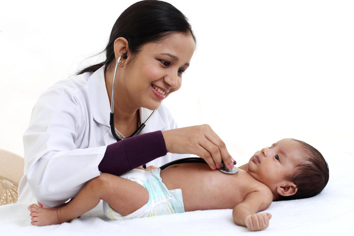 Cheerful female pediatrician holds newborn baby
