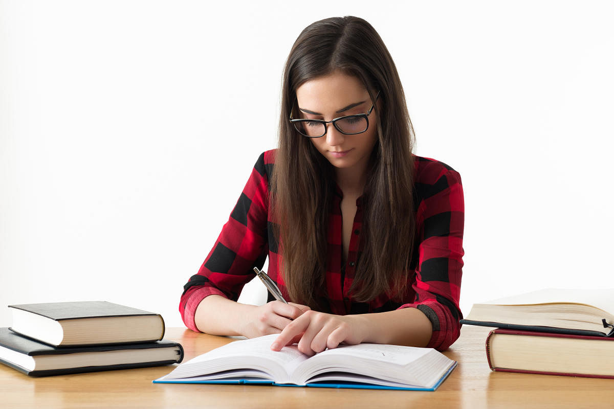 Attractive caucasian girl studying for her exams at home, education concept on white backgroundCaucasian girl studying for her exams at home, education concept