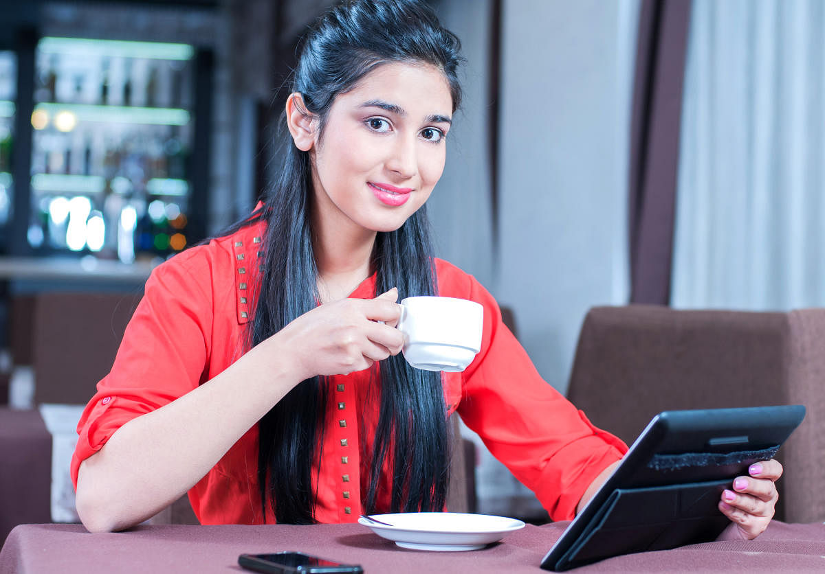 Young indian businesswoman on a coffee break. Using tablet computer.Cafe
