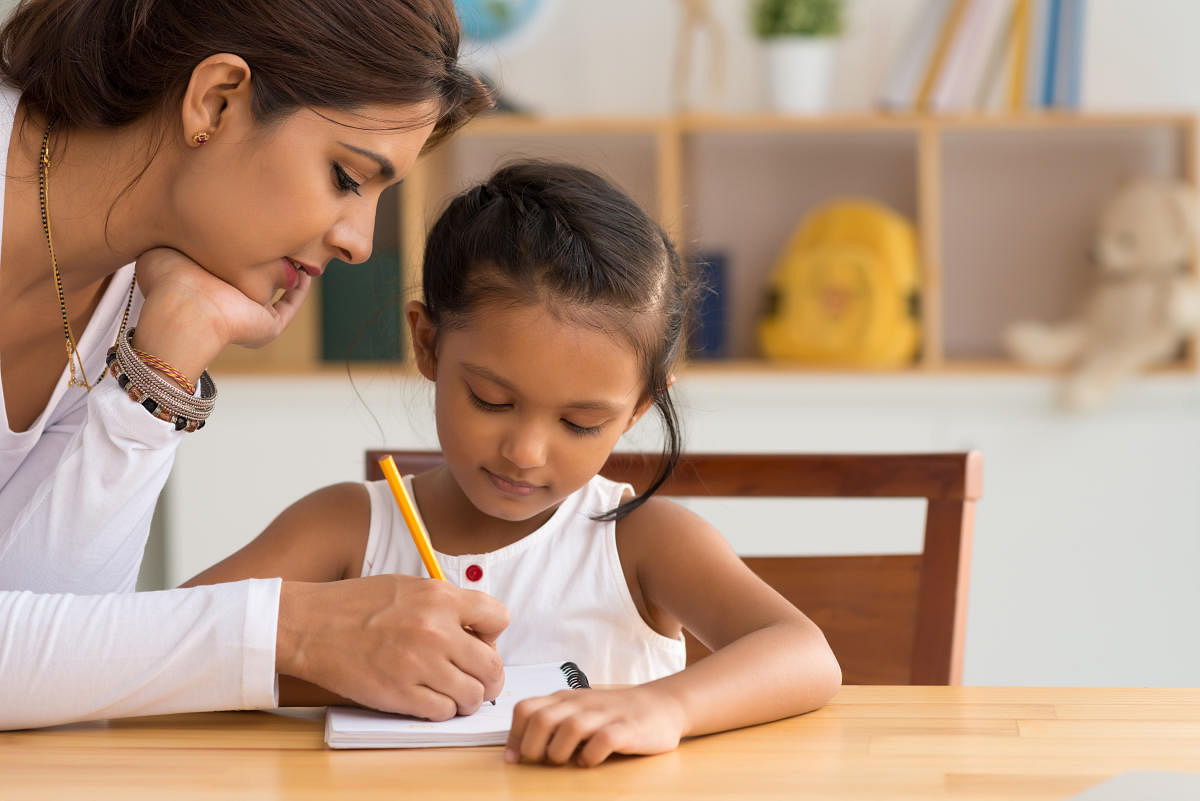 Beautiful Indian woman helping her daughter with homeworkHelping with homework