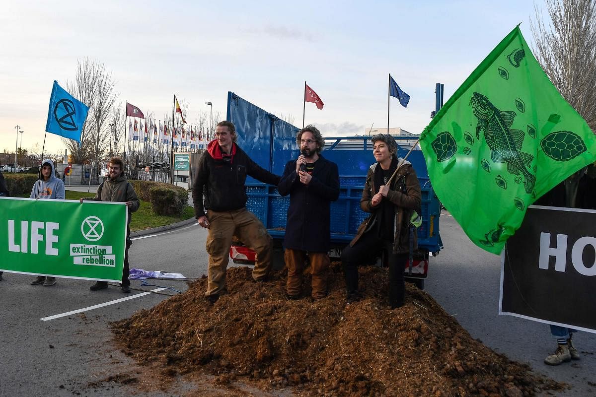 Activists from international climate action group Extinction Rebellion protest after dumping manure outside the UN Climate Change Conference COP25 at the 'IFEMA - Feria de Madrid' exhibition centre, in Madrid, on December 14, 2019. - A UN climate summit in Madrid risked collapsing on December 14 after all-night negotiations between countries left them more divided than ever over on how to fight global warming and pay for its ravages. Diplomats from rich nations, emerging giants and the world's poorest countries -- each for their own reasons -- found fault in a draft agreement put forward by host Chile in a botched attempt to strike common ground. (Photo by OSCAR DEL POZO / AFP)