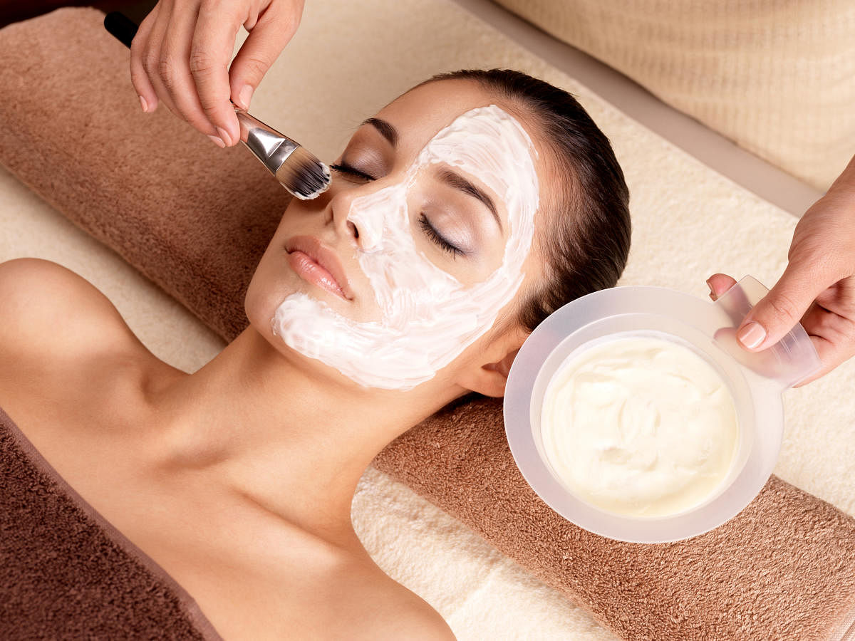 Spa therapy for young woman receiving facial mask at beauty salon - indoorsSpa therapy for woman receiving facial mask